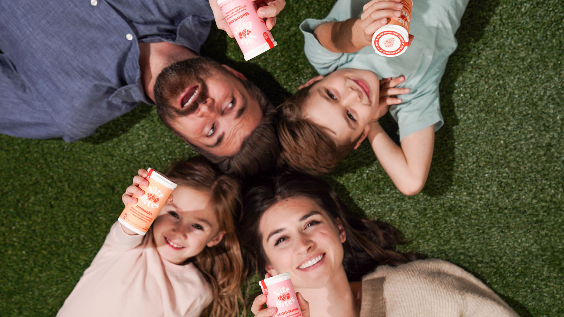 ViteBites Lifestyle Photography Family lying on grass holding ViteBites supplement containers
