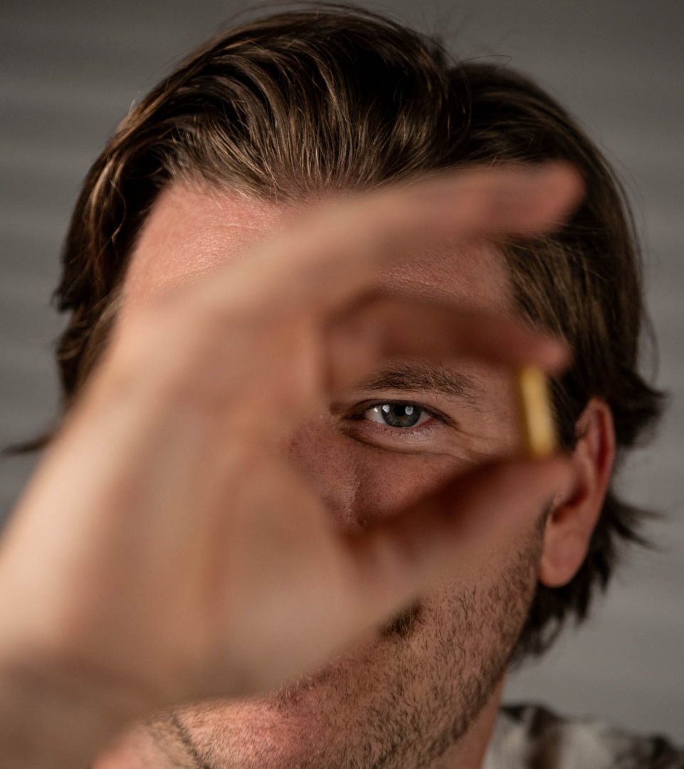 Ameo Life lifestyle photography with supplement capsule Person holding an Ameo Life supplement capsule near their face.